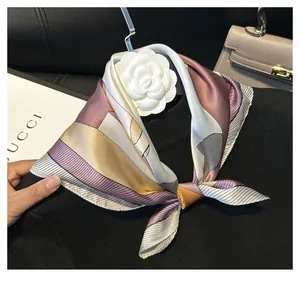 Detail of silk scarf with geometric purple gold pattern and white camellia flower accessory