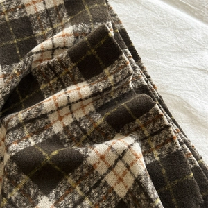 Nahaufnahme der dicken Retro-Karo-Schal-Textur mit orangefarbenen Strickfasern