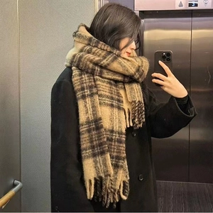 Gros plan d'une écharpe épaisse en mohair à carreaux avec franges aux tons terreux d'hiver