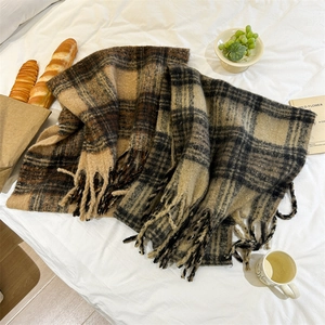 Écharpe en mohair à carreaux marron style Maillard avec franges sur un lit douillet