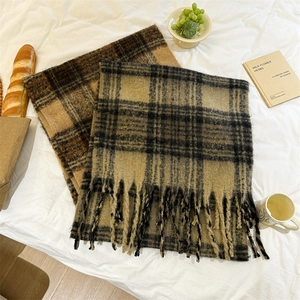 Détail de grandes écharpes à carreaux en mohair avec longues franges dans un décor hivernal