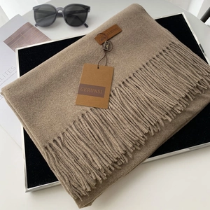 Classic camel cashmere-feel scarf with tassels and leather brand label on display