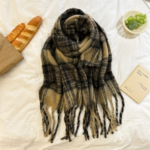Détail d'une écharpe en mohair à carreaux marron avec franges et décor chaleureux