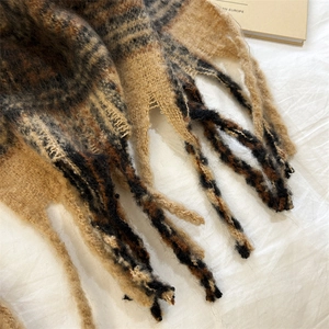 Gros plan sur une écharpe en mohair à carreaux marrons avec franges et maille douce