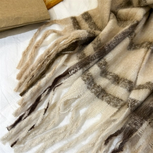 Gros plan d'une écharpe à carreaux beige et marron avec texture douce et détails de franges