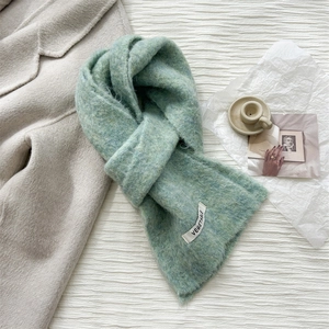 Detail of light green wool scarf with a vegetable label on soft fabric texture