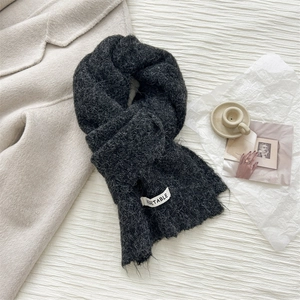 Detail of dark grey wool knit scarf with soft brushed texture and white design label