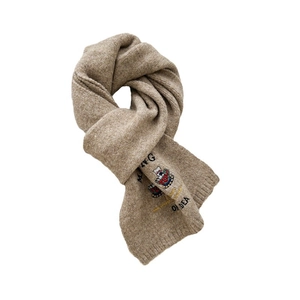 Gestrickter Wollschal in Haferfarbe mit Bären-Stickerei und weichem Fall auf weißem Grund