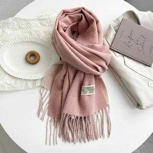 Detailed texture of pink cashmere-like scarf with fringe and a rectangular fabric label