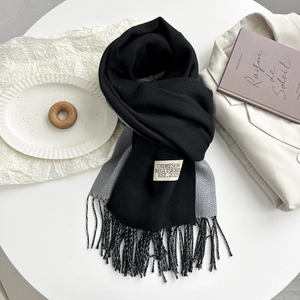 Detail of two-tone black and grey cashmere-like scarf with fringe and brand label