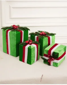 Détail de boîtes de Noël en velours vert ornées de cloches rouges et d'aiguilles de pin