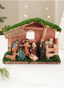 Detalle de figuras de pesebre pintadas a mano en un establo de madera con musgo