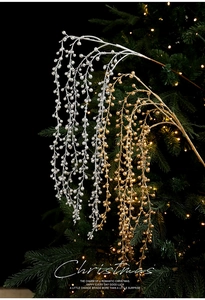 Close-up of sparkling gold and silver berry branches hanging on a lighted Christmas tree