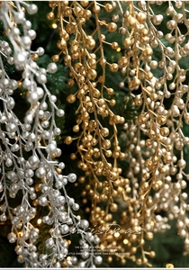 Close-up of glittery gold and silver Christmas berry stems with festive lights