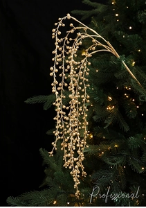 Detail of glitter gold berry pick hanging on Christmas tree with warm lights
