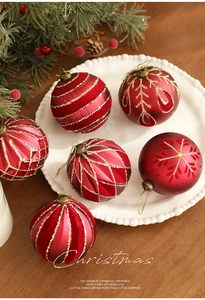 Close-up of six 8cm red matte Christmas balls with gold glitter patterns in a ceramic dish