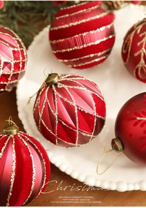 Macro detail of 8cm red Christmas ornaments with glitter patterns on a white plate