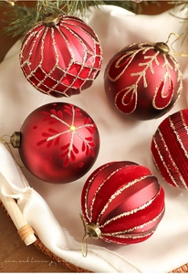 Detailed close-up of 8cm red Christmas balls with gold glitter patterns and pine branches