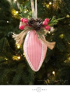 Detail of pink knitted Christmas ball ornament with pine cones and berries on a tree