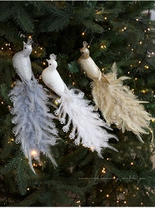 Close-up of glittery peacock Christmas ornaments with feathers on a festive tree branch