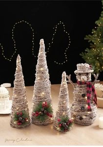 Sapins de Noël en rotin lumineux et bonhomme de neige sur une table en bois