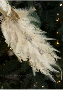 Detail of Christmas bird ornament with white feathers and gold glitter on tree branch