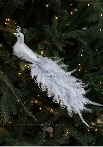 Detailed view of a silver glitter peacock ornament with blue feathers on a Christmas tree