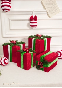 Detail of red velvet Christmas gift boxes with green ribbons and mini bells on pine needles