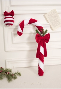Detail of red and white velvet candy cane ornament with festive bow and pine needles