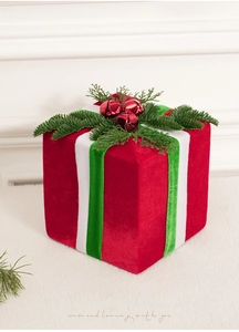 Close-up of red velvet Christmas gift box with pine needles and bells on white fur