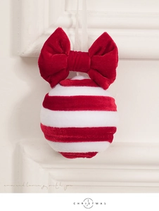 Detail of red and white striped plush Christmas ball ornament with velvet bow accent