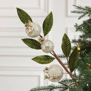 Macro shot of gold glitter pomegranates with green velvet leaves on decorative branch