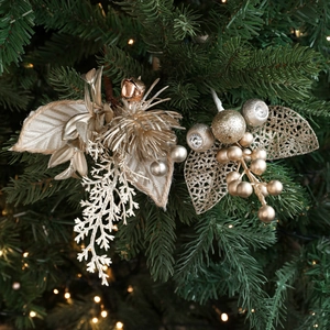Elegant champagne gold Christmas picks with glitter balls and leaves on a lit pine tree