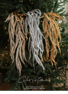 Detail of glitter fern branches in gold and silver hanging on a lighted Christmas tree