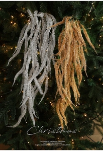 Detail of glittered willow leaves hanging on a Christmas tree with warm lights