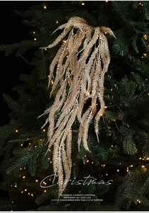 Close-up of golden glitter willow branch hanging on a Christmas tree with warm bokeh lights