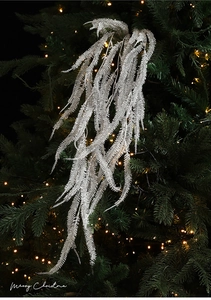 Macro detail of glittery silver artificial fern branch on a Christmas tree with lights