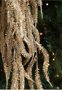 Macro shot of glittering gold pine needle branch decorations on a Christmas tree