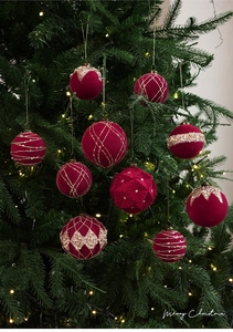 Detalle de bolas de Navidad de terciopelo rojo con purpurina dorada en un árbol festivo