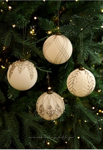 Detalle de bolas de Navidad crema con purpurina dorada y perlas en un árbol