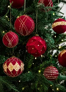 Close-up of luxury burgundy velvet Christmas baubles with gold glitter on a tree