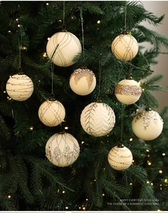 Detalle de bolas de Navidad blanco crema con motivos dorados brillantes en árbol