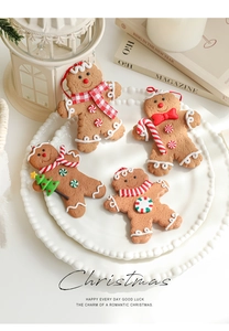Detail of 4-piece gingerbread man ornaments with festive scarves on a white vintage tray