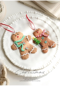 Two gingerbread man ornaments with scarves on a white plate for Christmas decor