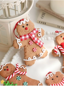 Close-up of gingerbread man ornaments with scarf and candy cane on a festive background