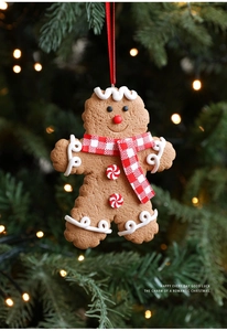 Gingerbread man ornament with red scarf hanging on a festive Christmas tree