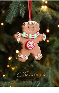 Close-up of clay gingerbread man ornament with red scarf on a glowing Christmas tree