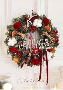 Detail of Christmas wreath with velvet balls, pine cones and warm LED lights on white wall