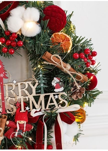 Detail of burgundy Christmas wreath with LED lights, cotton, pine cones, and Merry Christmas sign