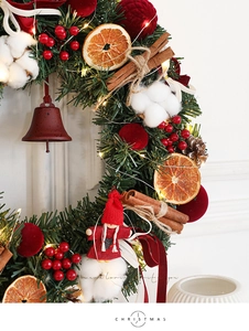 Detail of Christmas wreath with warm LED lights, red berries, and cinnamon sticks
